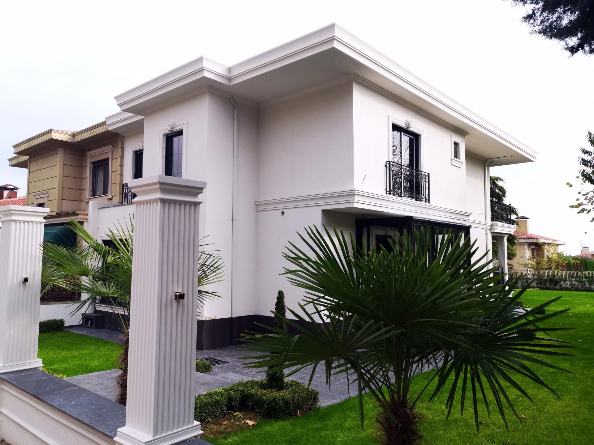 Beyaz villa dış cephesinde kullanılan poliüretan pencere söveleri ve bahçe girişinde yivli pilaster sütun modeli.
