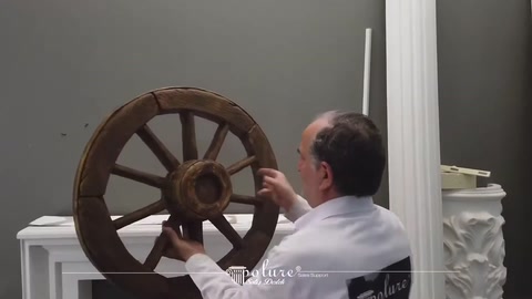 Sunucu duvardaki koyu renkli dekoratif at arabası tekerini inceliyor