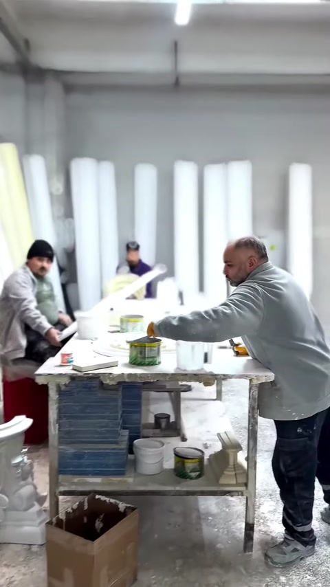 Usta, geniş üretim tezgâhında beyaz dekoratif parçalar üzerinde çalışıyor.