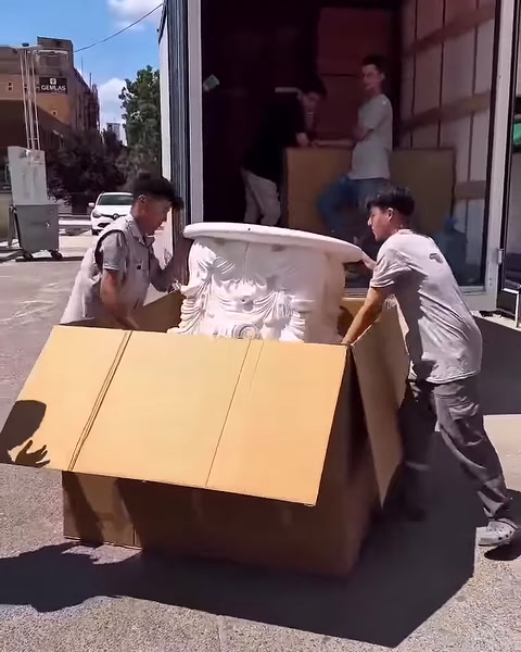 İki çalışan, işlemeli sütun başlığını kutudan dikkatle çıkarıyor.