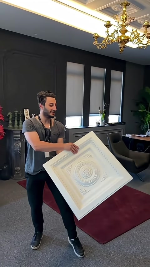 Geometrik tavan paneli elde tutularak önden sergileniyor