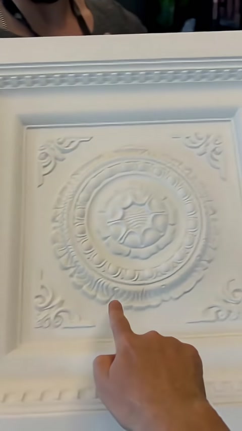 Panel merkezindeki çiçek desenli kabartma rozet işaret ediliyor