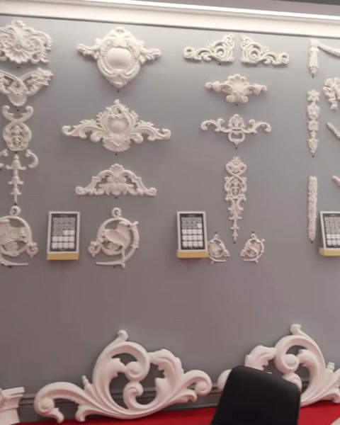 Farklı biçimlerdeki beyaz dekoratif motifler sergi duvarında birlikte görülüyor