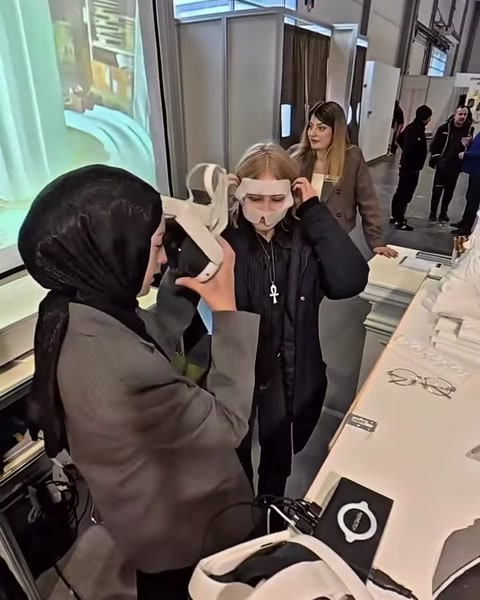 Ziyaretçiye hijyen maskesi üzerinden VR gözlüğü dikkatle takılıyor