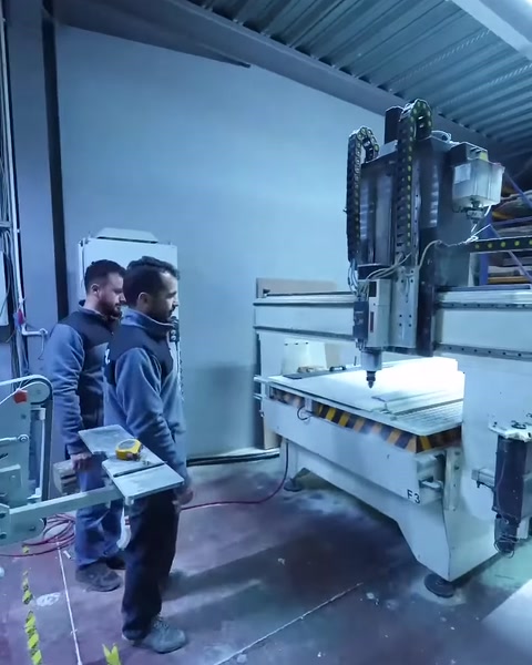 Çalışanlar CNC makinesi yanında üretim hazırlığını kontrol ediyor