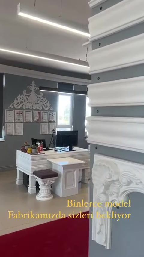 Tavan kartonpiyerleriyle çevrili showroomda çalışma masası ve numuneler görülüyor