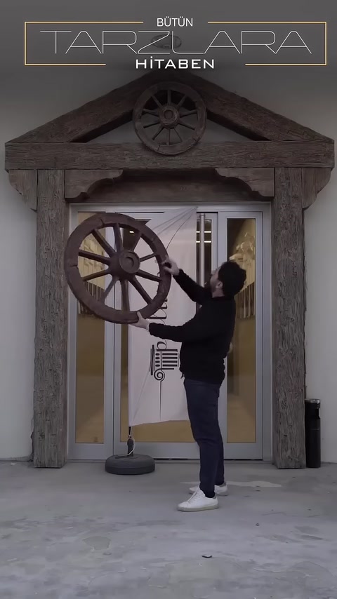 Rustik giriş düzeninde dekoratif at arabası tekerleği sergileniyor