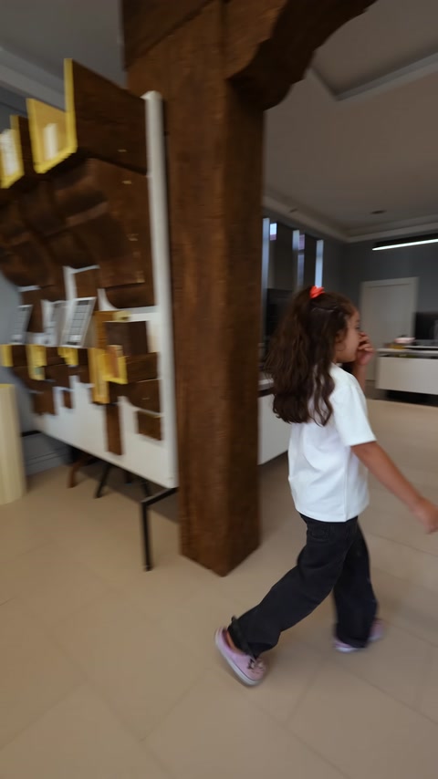 Ahşap görünümlü kalın kirişler showroom geçişinde yakından görülüyor.