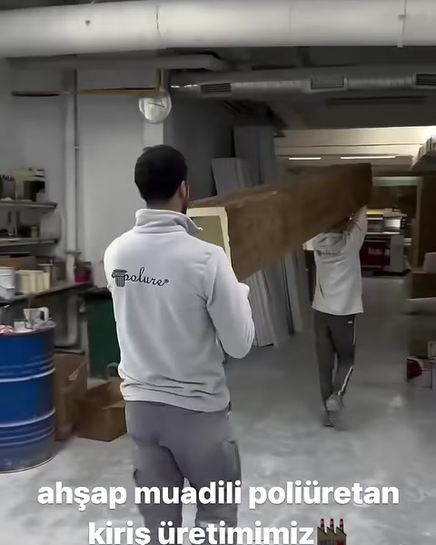 İki çalışan uzun ahşap dokulu kirişi birlikte taşıyor