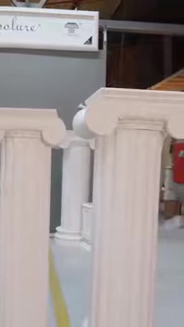 Kıvrımlı başlıklara sahip üç dekoratif sütun modeli birlikte duruyor