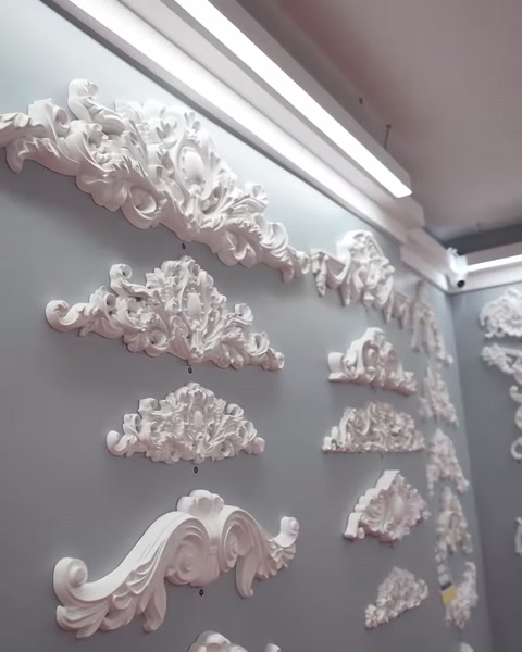 Farklı biçimlerdeki beyaz pediment modelleri sergi duvarında sıralanıyor.